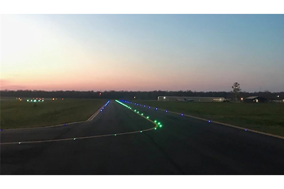 Blue and green illuminated markers on a paved area at dusk